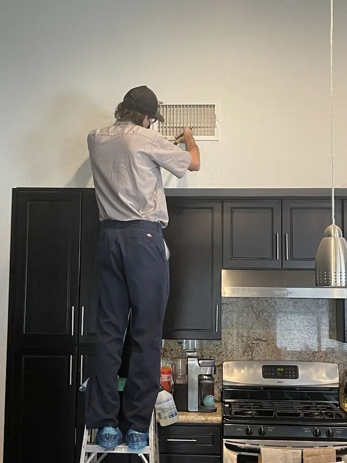 Technician inspecting an air vent during HVAC service in Schaumburg